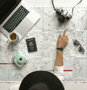 map with passport, camera, sunglasses, and laptop on top